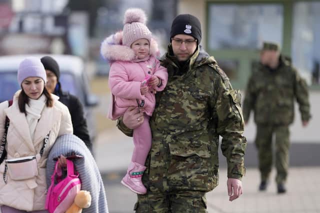 A Polish border guard carries a child as refugees from Ukraine cross into Poland at the Medyka crossing. (AP Photo/Markus Schreiber)