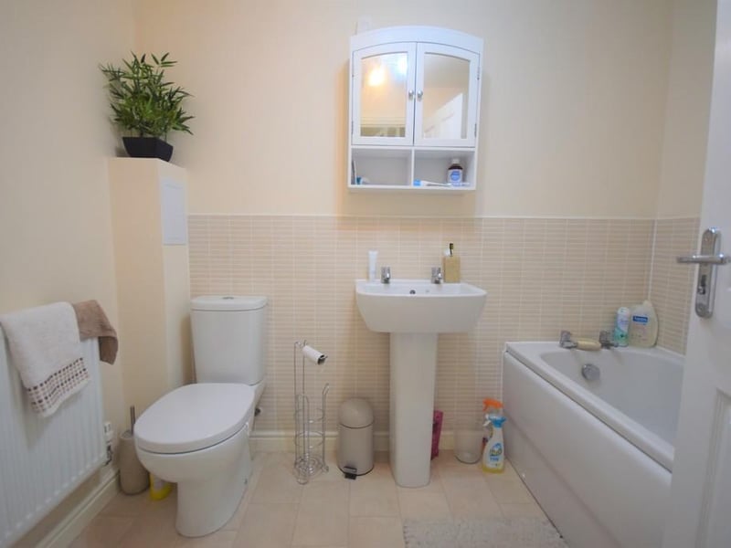 Three piece suite has a panelled bath with chrome taps, wash hand basin, low flush wc and tiled splashbacks to the wall areas.