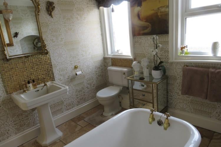 The family bathroom has a free standing roll top bath and pedestal wash basin