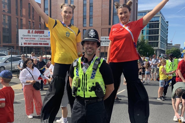Fans on stilts pose for pictures with police officers