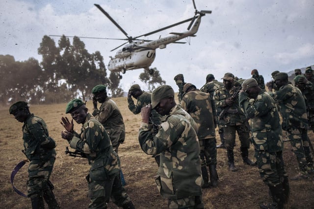 Congolese army soldiers protect their faces from debris when a United Nations Organization Stabilization Mission in the Democratic Republic of the Congo (MONUSCO) helicopter lands in Bijombo.