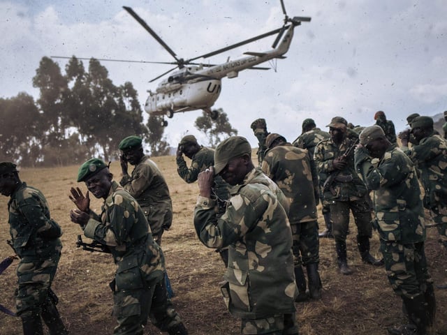 Congolese army soldiers protect their faces from debris when a United Nations Organization Stabilization Mission in the Democratic Republic of the Congo (MONUSCO) helicopter lands in Bijombo.