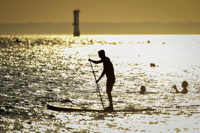 A stand up boarder in the evening sunshine on Southsea beach taken by Finnbarr Webster/Getty Images