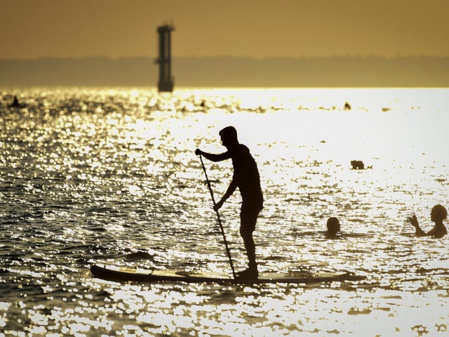 A stand up boarder in the evening sunshine on Southsea beach taken by Finnbarr Webster/Getty Images