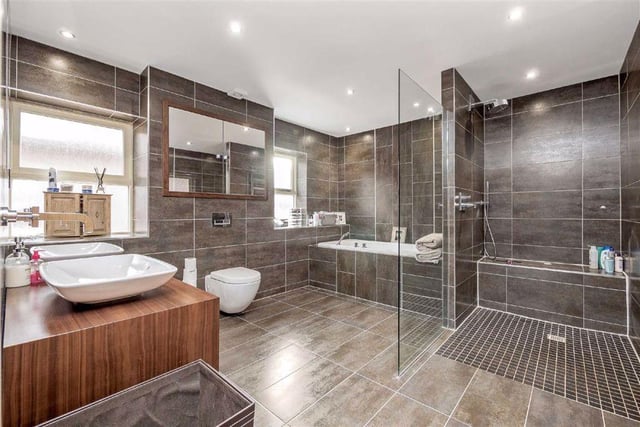 Six bathrooms are located throughout the property, with this stylish family room featuring marble effect tiling, a bath, twin sinks and a large walk-in shower.