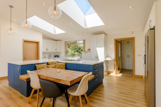 The bespoke kitchen has a range of wall and base units and a centre island with quartz countertop and bespoke integrated seating area which is the "heart of the home".