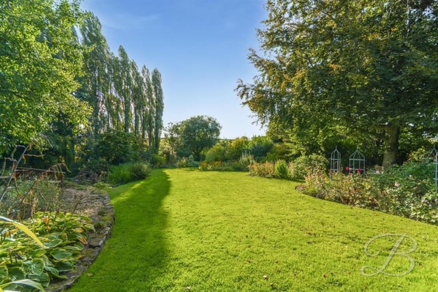 The rear garden has a maintained lawn which is surrounded by mature trees and well-established plants.