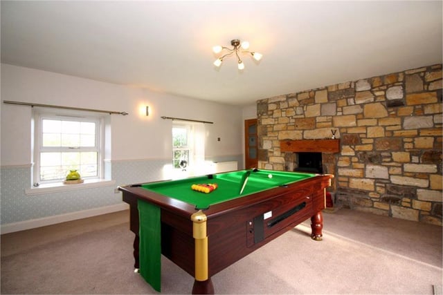 Living room/games room with feature stone wall and fireplace.