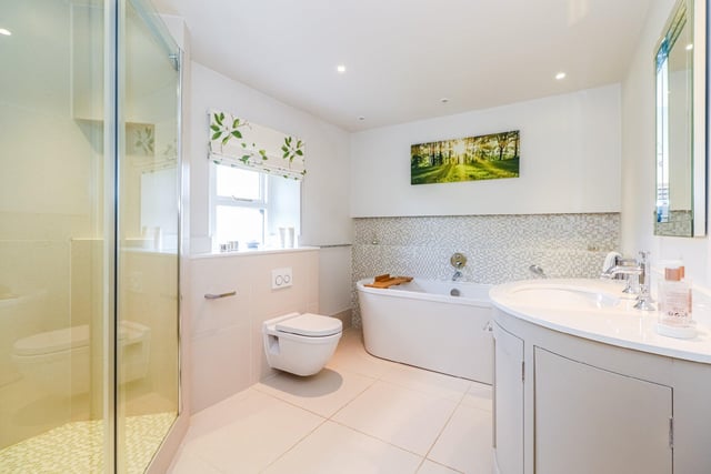The property features four bathrooms in total, including this stylish house bathroom complete with a double ended bath with shower attachment, separate shower cubicle, vanity wash basin, tiled floors and limestone top and curved cupboards.