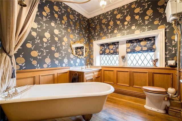 The main house bathroom is situated on the second floor, with a stand alone bath facing windows overlooking the grounds, toilet, sink and wooden flooring.
