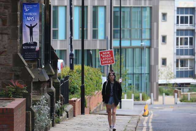 A woman walks past a sign outside a church, thanking the workers of Britain's NHS in Sheffield (Photo by LINDSEY PARNABY/AFP via Getty Images).
