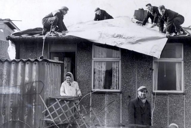 Residents of Skye Edge Avenue get a roof over their heads as workmen lay tarpaulin to protect their hurricane ravaged homes, February 17, 1962