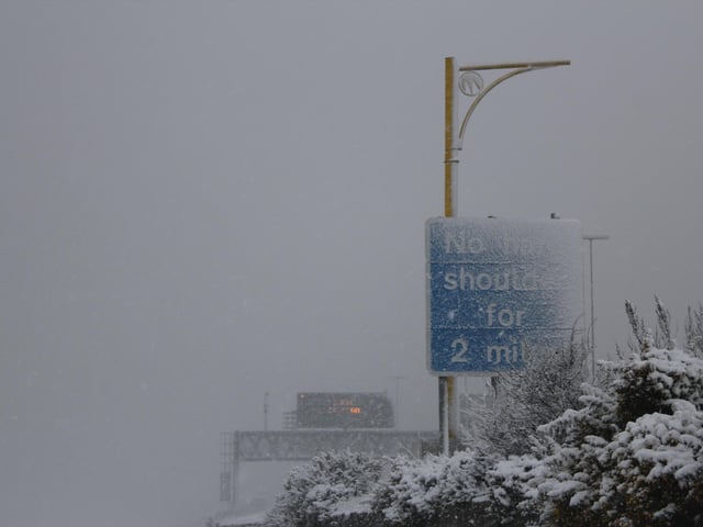 As if its blanket coating wasn't already enough, new snow falls heavily near one of Portsmouth's main roads.