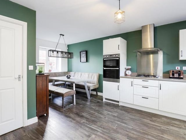 Here's another view of the kitchen, which shows the dining area and space for a dining table. There is also an integrated oven, a gas hob and glass, curved extractor hood, plus an integrated dishwasher and an integrated fridge freezer.