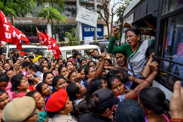 An activist (R in green) of left-wing parties shouts slogans from a bus after being detained by security personnel as she has been protesting with other activists against India's new citizenship law and for more action for women safety, during a demonstration in Guwahati on March 6, 2020. (Photo by Biju BORO / AFP) (Photo by BIJU BORO/AFP via Getty Images)