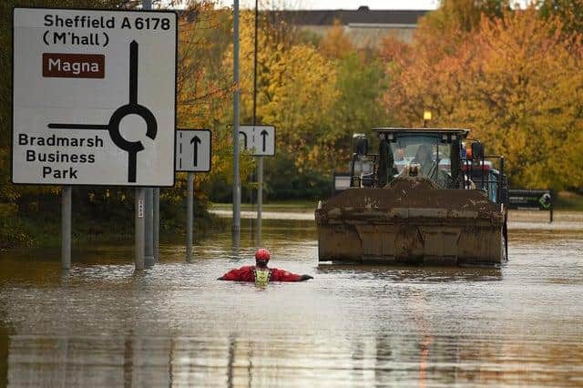 A member of the Fire and rescue service wades through flood water as he escorts a JCB towing an truck along a flooded road in Rotherham. (Photo by Oli SCARFF / AFP) (Photo by OLI SCARFF/AFP via Getty Images)