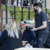 A waiter serves people in Sheffield wearing a mask because of coronavirus restrictions