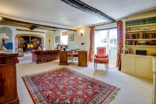 The spacious lounge boasts exposed beams, an inglenook fireplace with a large log burner, and French doors with views over the beautiful gardens