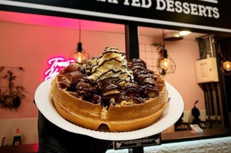 A waffle topped with icec ream and chocolate sauce.