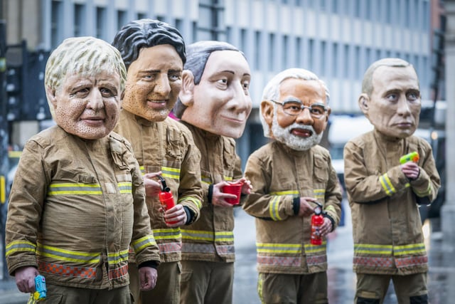 Campaigners wearing 'big heads' of world leaders, including Boris Johnson, Justin Trudeau and Narendra Modi gather for Oxfam's 'Ineffective Fire-Fighting World Leaders' protest performance during the official final day of the Cop26 summit in Glasgow. Picture date: Friday November 12, 2021.