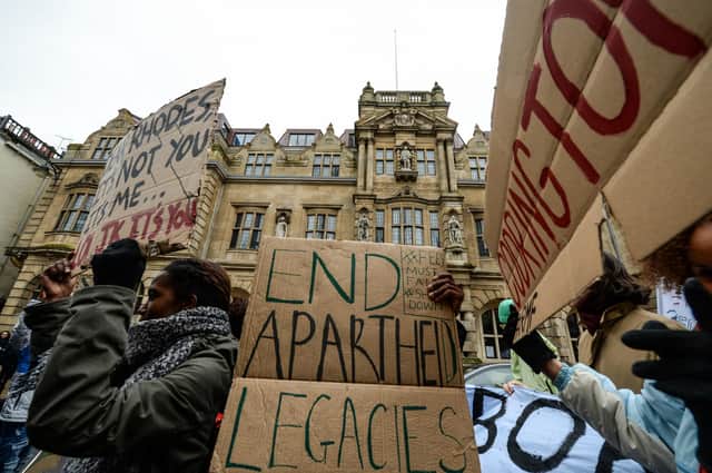 Students march past Oxford University's Oriel College and the statue of Cecil Rhodes that they are campaigning to be removed