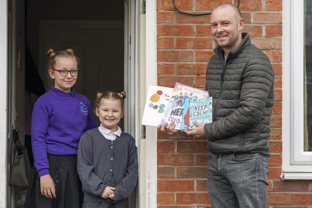 Mathew Webb, assistant head teacher at Swallownest Primary School, delivering the first of the donated books to pupils Mia and Lillyanne Astle