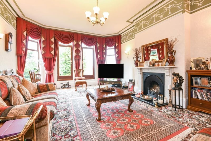 The "imposing and well-appointed" lounge boasts an open fireplace, coving to the ceiling and a central heating radiator. There are also full-length, side-facing, double-glazed windows allowing an abundance of natural light within.