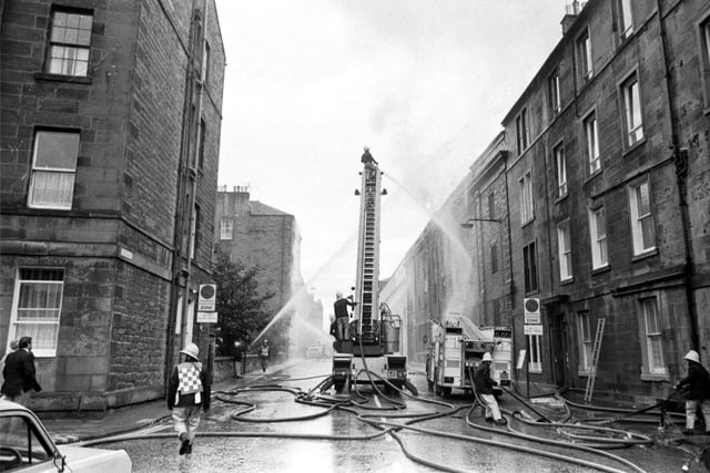 A fireman on a ladder directs water onto a fire at a warehouse next to Bertrams' engineering works in Sciennes, Edinburgh, September 1983.