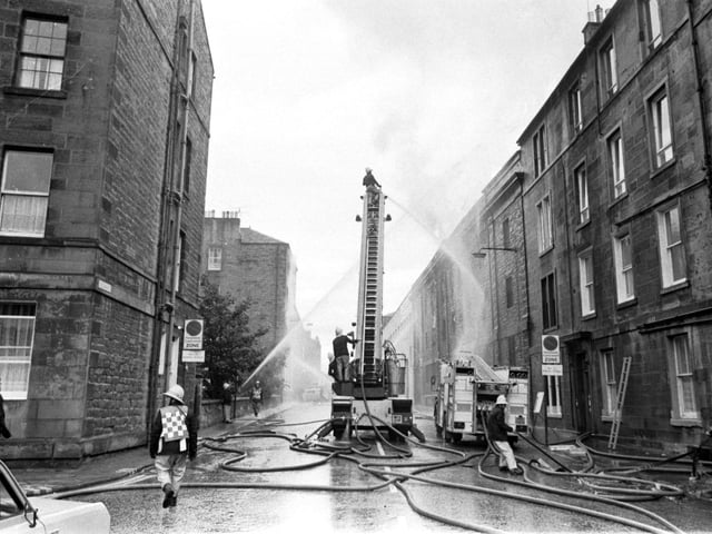 A fireman on a ladder directs water onto a fire at a warehouse next to Bertrams' engineering works in Sciennes, Edinburgh, September 1983.