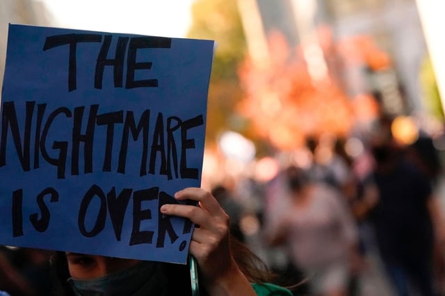 A woman holds a sign reading "The Nightmare is Over" as people celebrate on Black Lives Matter plaza across from the White House in Washington, DC (Photo by ALEX EDELMAN/AFP via Getty Images)