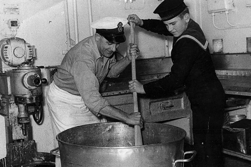 Stirring the Christmas  pudding on HMS Maidstone
Here we see the late Chief Petty Officer Les Russell and youngest sailor Jerry Locke stirring the Christmas mix.
Maureen Maidment sent in this photograph of her father and the youngest member of the crew, Jerry Locke from Portchester, stirring the Christmas  pudding with a paddle. It was taken aboard HMS Maidstone, a submarine depot ship, in  December 1954.