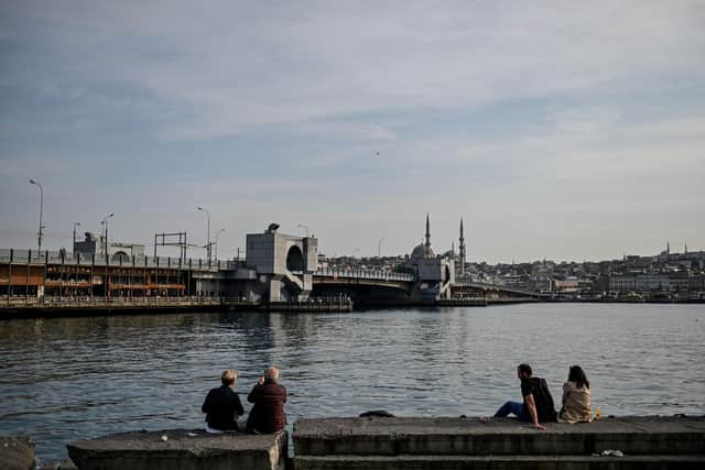 People sit on the shore side of Bosphorus strait in front of Galata Bridge: OZAN KOSE/AFP via Getty Images