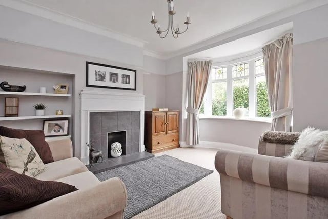 The bay fronted living room has a period style feature fireplace with wooden surround, tiled inset and raised hearth, neutrally decorated with period features.