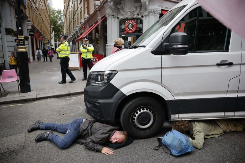 Climate activists from the Extinction Rebellion group lock on under a van they parked blocking a road in central London on August 23, 2021 as the group launched its 'Impossible Rebellion' series of actions (Photo by TOLGA AKMEN/AFP via Getty Images)