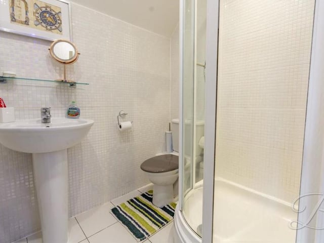 The en suite to the master bedroom is compact but pleasant. It comprises an enclosed shower cubicle, a low-flush WC and a pedestal sink.