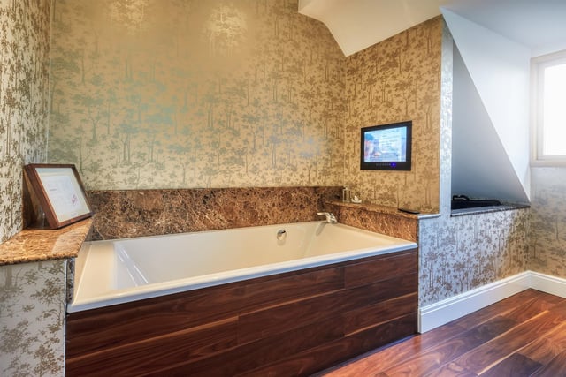 This house bathroom is one of four bathrooms throughout the property and includes a high quality suite, complete with a marble surround bath and inset television, WC, vanity unit and vertical radiator.