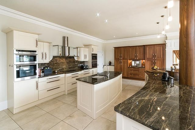 A bespoke kitchen is fitted with an extensive range of cream and wood fronted units, including two islands with granite work surfaces and fitted appliances. The kitchen also benefits from a glass breakfast bar, further built in dining area and French doors set within a large bay window (not pictured).