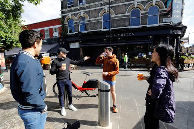 Customers chat as they drink their takeaway draught beer in plastic cups outside a pub (Photo by Tolga AKMEN / AFP) (Photo by TOLGA AKMEN/AFP via Getty Images)