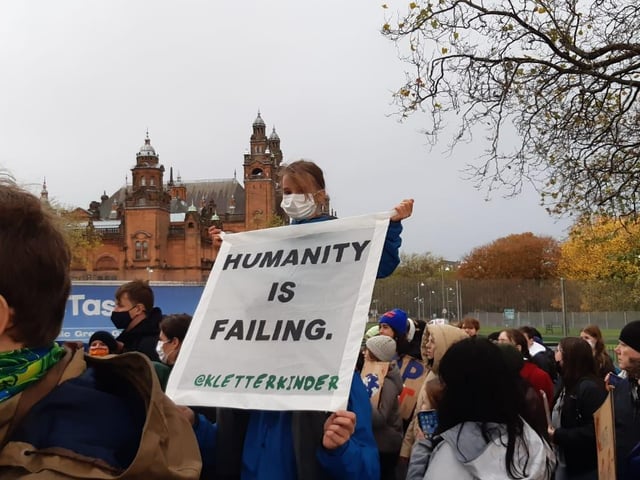 An activist with a sign which reads: "Humanity is failing."
