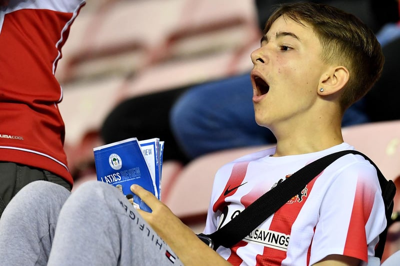 A Sunderland fan enjoys reading the programme before the game.