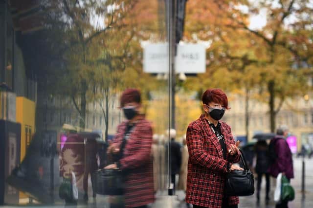 A woman is reflected in a window as she leaves a shop in central Sheffield (Photo by OLI SCARFF/AFP via Getty Images)