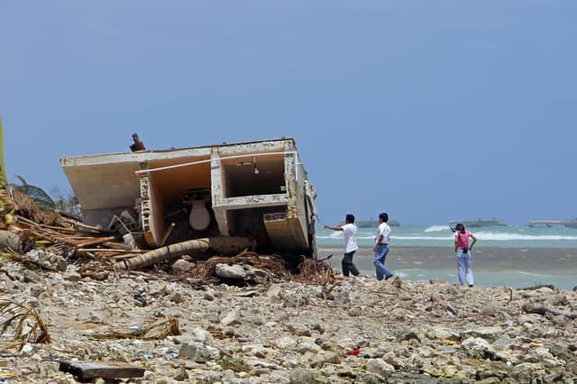 People look at the remains of a destroyed house on Mahahual's beach, 80 km from Chetumal, 22 August 2007, after the passage of Hurricane Dean., which made landfall in the beaches of Mexico on August 21, 2007.