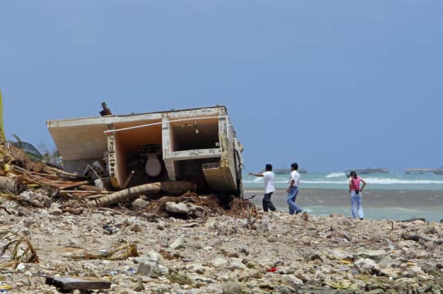 People look at the remains of a destroyed house on Mahahual's beach, 80 km from Chetumal, 22 August 2007, after the passage of Hurricane Dean., which made landfall in the beaches of Mexico on August 21, 2007.