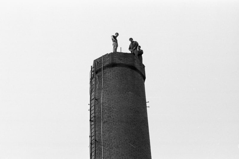 Three men stand on top of the Royal Infirmary of Edinburgh in Lauriston Place  - on the day the old boilerhouse chimney was demolished in February 1984.
