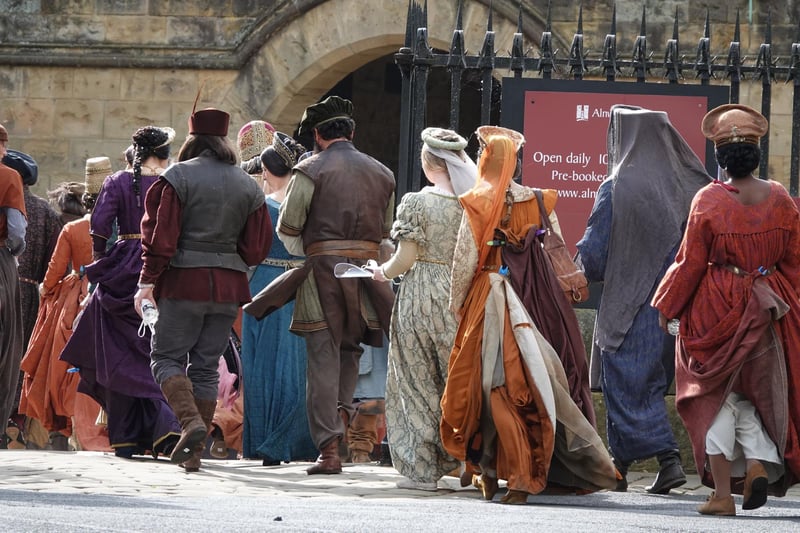 A party of extras in medieval costumes enter the castle.