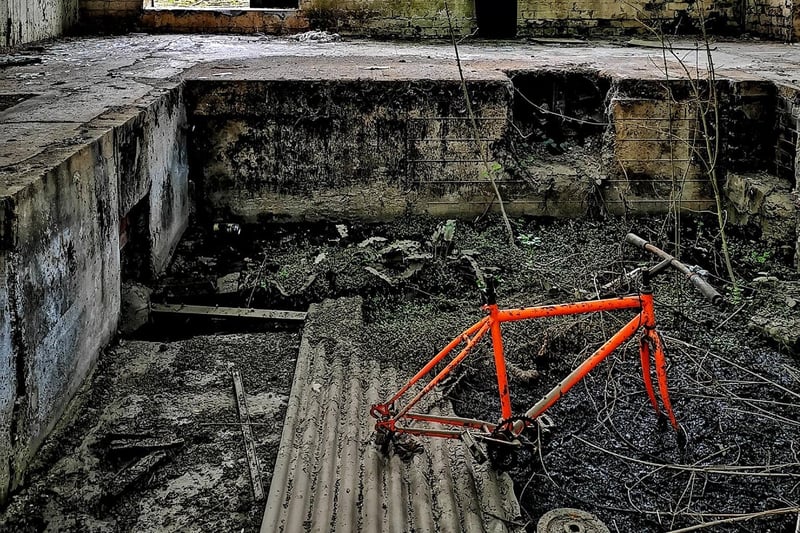 An orange bike frame has been abandoned in the building.