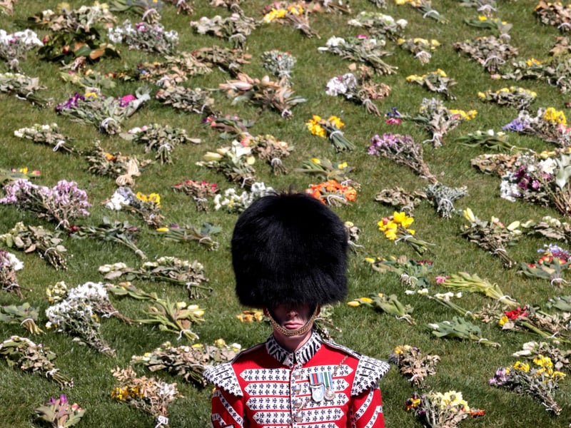 A guard stands in front of flowers laid out on the grass outside St George's Chapel for Prince Philip.