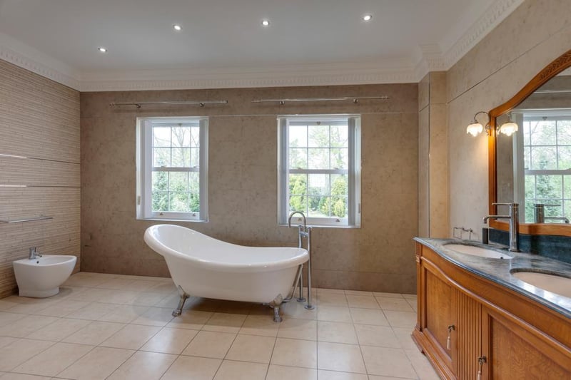 The master ensuite boasts a freestanding roll-top bath with a chrome mixer tap in front of the front-facing, upvc double-glazed sash windows.