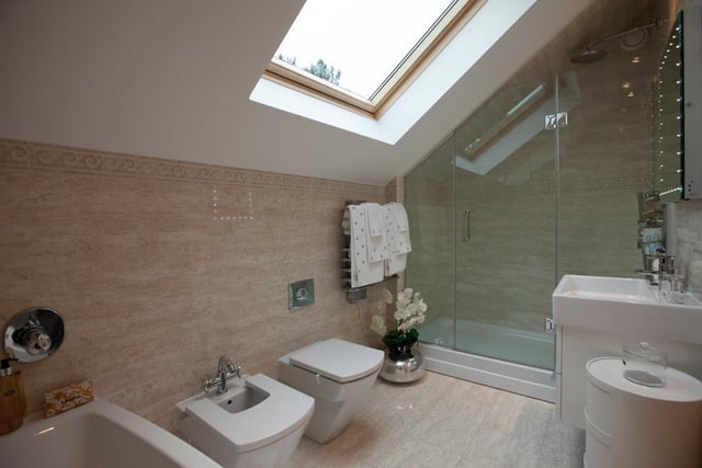 The master en-suite is fully tiled and has a Velux roof window, wall-mounted spotlights, a panelled bath and a separate shower enclosure with a fitted rain head shower.