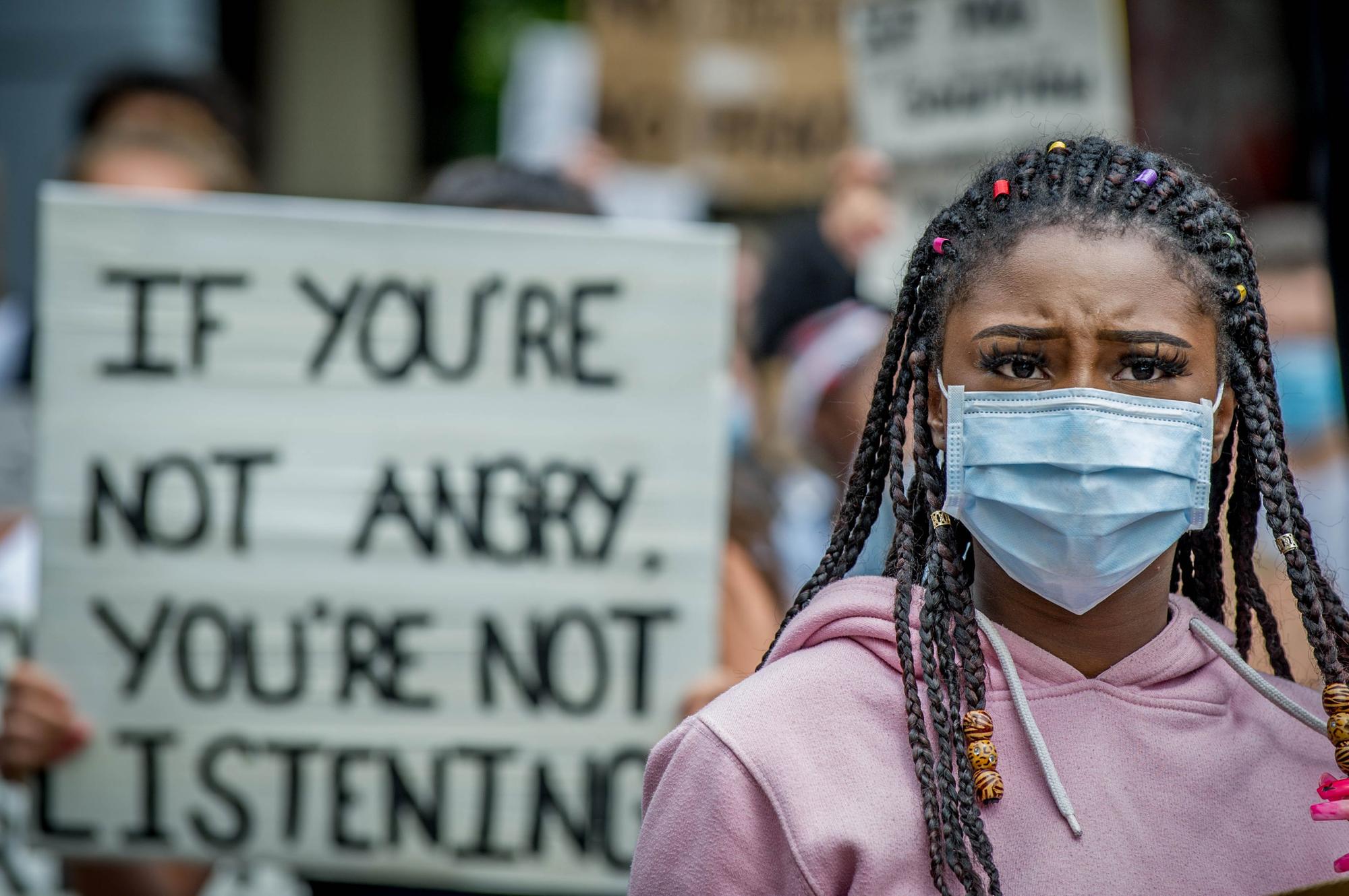 A demonstrator outside Portsmouth Guildhall listens to a speaker as she stands in front of a poignant message.